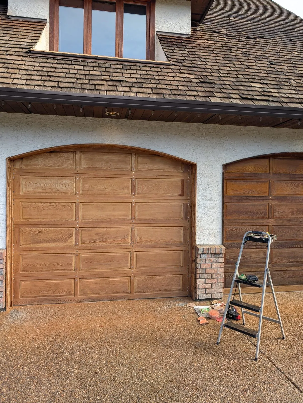 Faded cedar garage doors with worn stain on a Metro Vancouver home before restoration