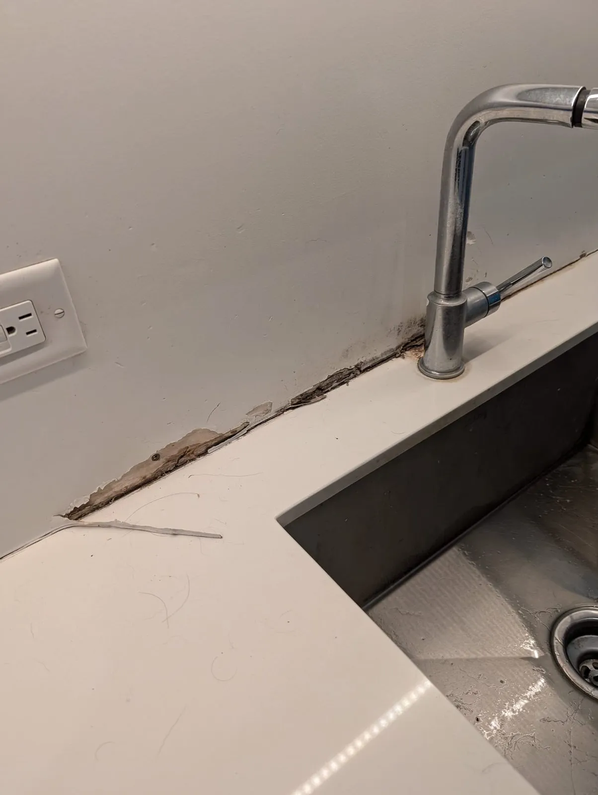 Water-damaged kitchen counter and drywall around sink in Metro Vancouver home