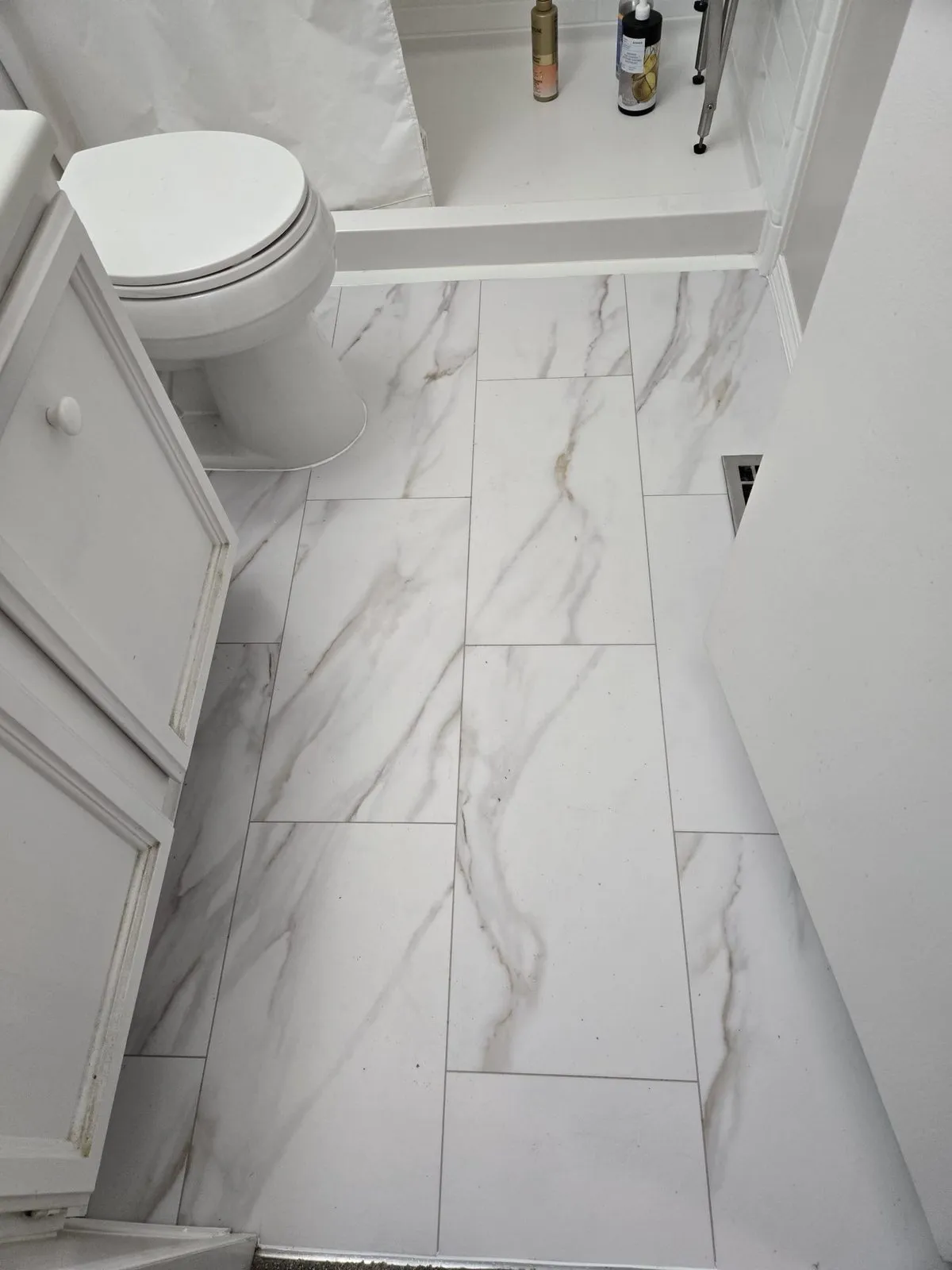 Bright marble-effect porcelain tile installed with clean grout and trim by our handyman team