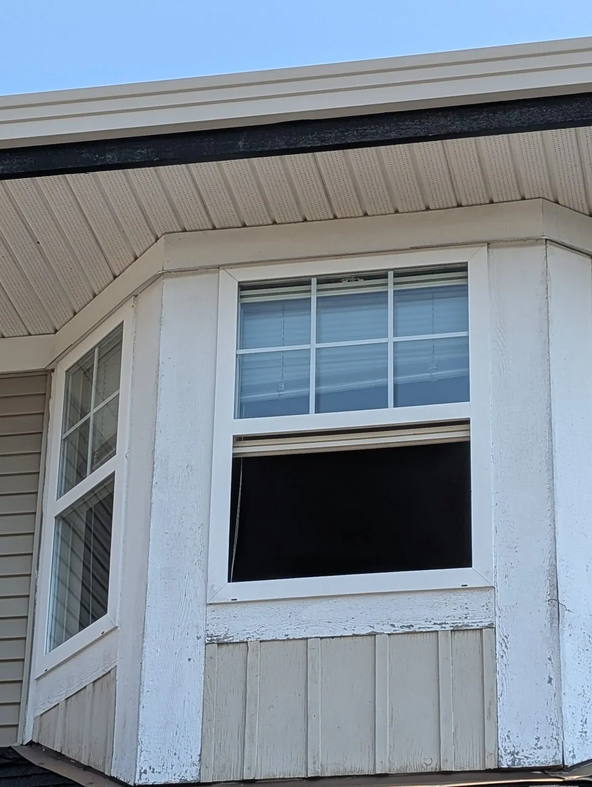 Peeling paint and worn siding under a second-storey bay window before repair