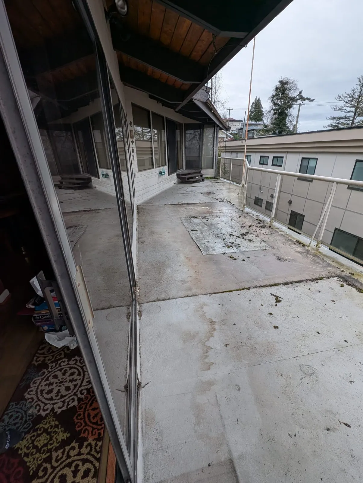 Stained and patched sundeck surface with moss and old seams before resurfacing in Metro Vancouver